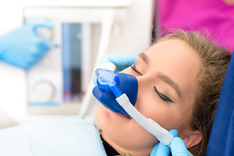 A woman in a dentists chair with a sleep mask.