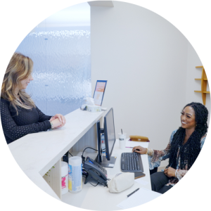 Two women speaking at a reception desk.