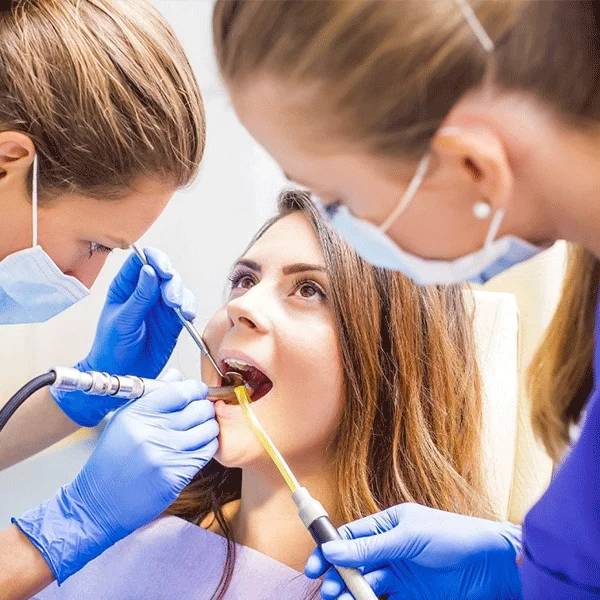 Dental professional examines patient's teeth in bright clinical setting with dental tools